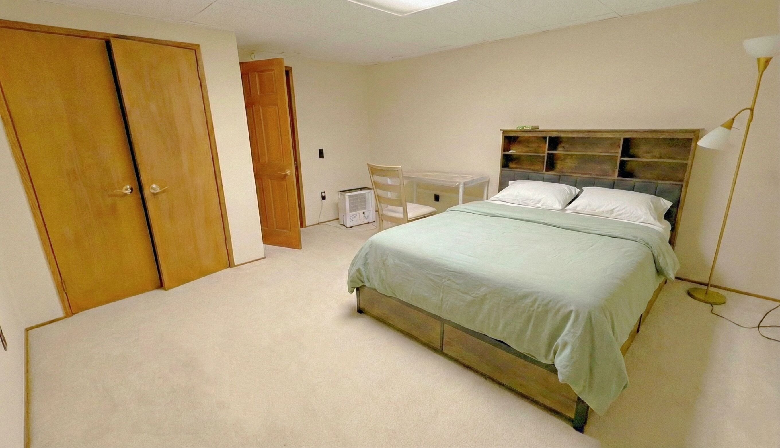 Ein Schlafzimmer mit einem Bett, einem Holzschrank, einem Sessel und einem Nachttisch.