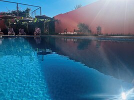 Una piscina al aire libre, sillones reclinables de piscina