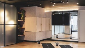A modern gym with wooden floors, exercise mats, kettlebells, and a large mirror. - The Central Mount-Balcony-Gym-Parking (Manchester)