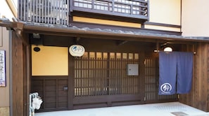 Ein traditionelles japanisches Gebäude mit einem hölzernen Eingangstor, einem kleinen Schild und einem blauen Vorhang.