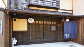 Ein traditionelles japanisches Gebäude mit einem hölzernen Eingangstor, einem kleinen Schild und einem blauen Vorhang.