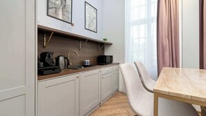 Een moderne keuken met grijze kastjes, een houten aanrecht en een eethoek met een marmeren tafel en een stoel.