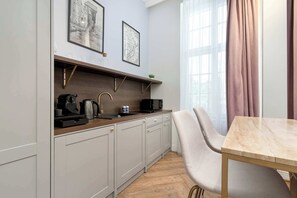 Eine moderne Küche mit grauen Schränken, einer Holzarbeitsplatte und einem Essbereich mit einem Marmortisch und einem Stuhl.