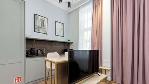 Een moderne keuken met een flatscreen televisie, een houten bankje en een kleine tafel.