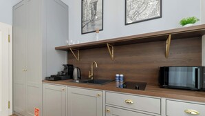 Een moderne keuken met grijze kastjes, een houten aanrechtblad, een zwarte magnetron en een koffiezetapparaat.