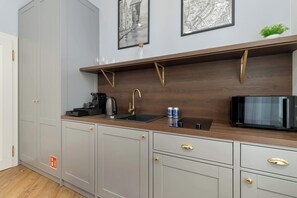 Eine moderne Küche mit grauen Schränken, einer Holz Arbeitsplatte, einer schwarzen Mikrowelle und einer Kaffeemaschine.