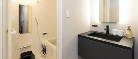 A modern bathroom with a black vanity, a mirror, a shower, and a small stool.