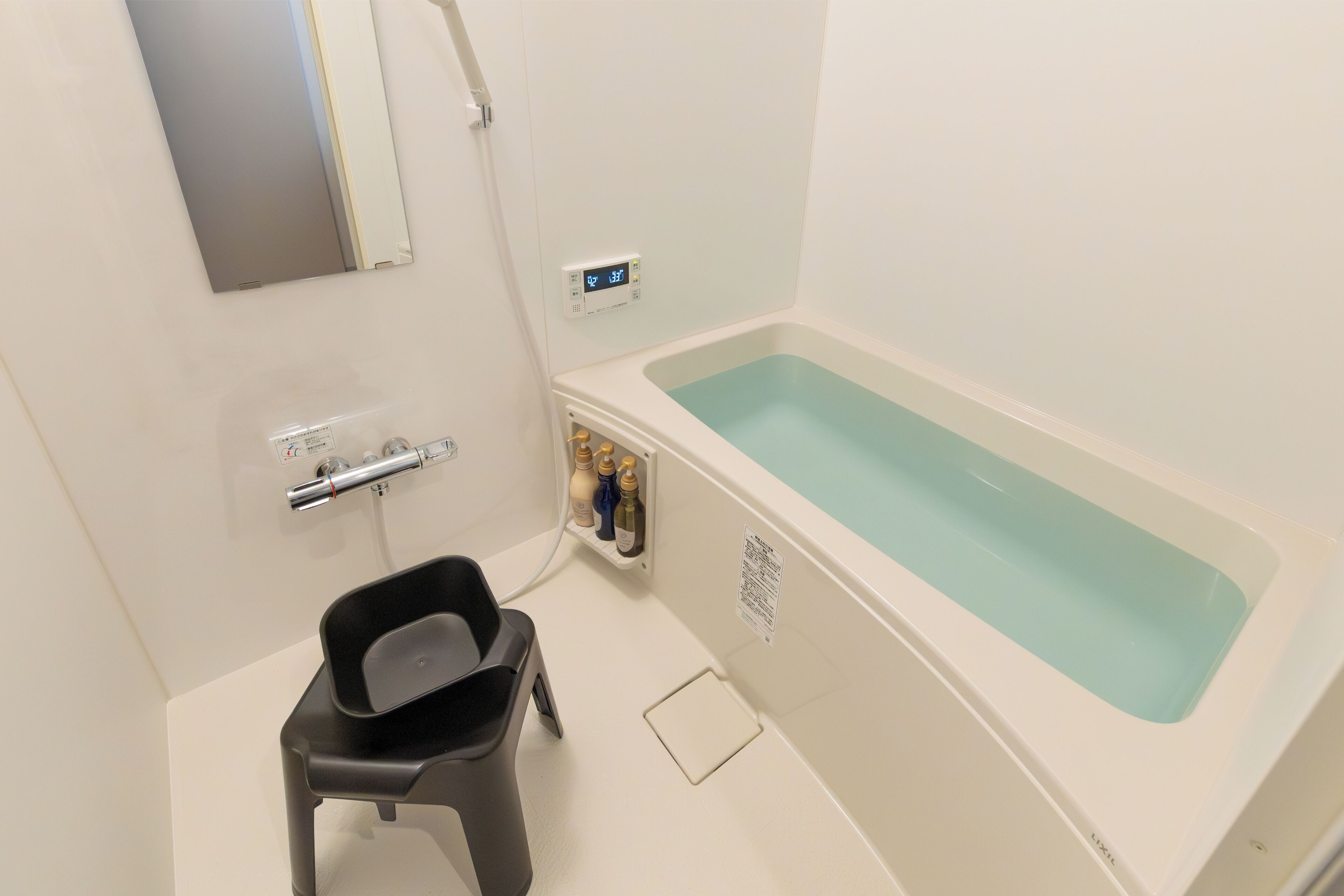 A bathroom with a bathtub, a shower, a toilet, and a small stool.