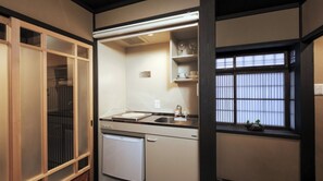 Eine kleine Küche mit Kühlschrank, Spüle und Fenster mit Jalousien.