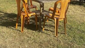 Une table et quatre chaises sont disposées sur une pelouse, avec une chaîne de montagnes en arrière-plan.