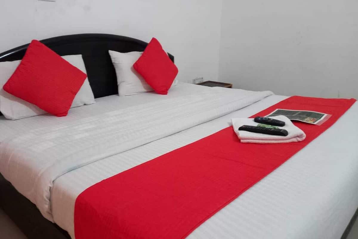 A neatly made bed with a white and red bedspread, two red pillows, and a red blanket.