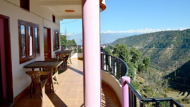 Un balcon avec une table et des chaises, donnant sur un paysage montagneux.