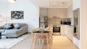 A modern apartment with a dining area, a sofa, and a kitchen. - Bloomfields Iconic 1BR Waters Edge (Abu Dhabi)