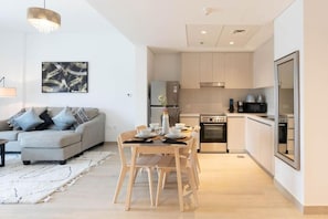 A modern apartment with a dining area, a sofa, and a kitchen. - Bloomfields Iconic 1BR Waters Edge (Abu Dhabi)