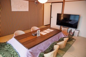 A traditional Japanese room with tatami flooring, a low wooden table, and a television.