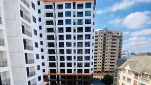 Un edificio residenziale a grattacielo con numerosi balconi, una piscina sul tetto e un'area giardino curata.