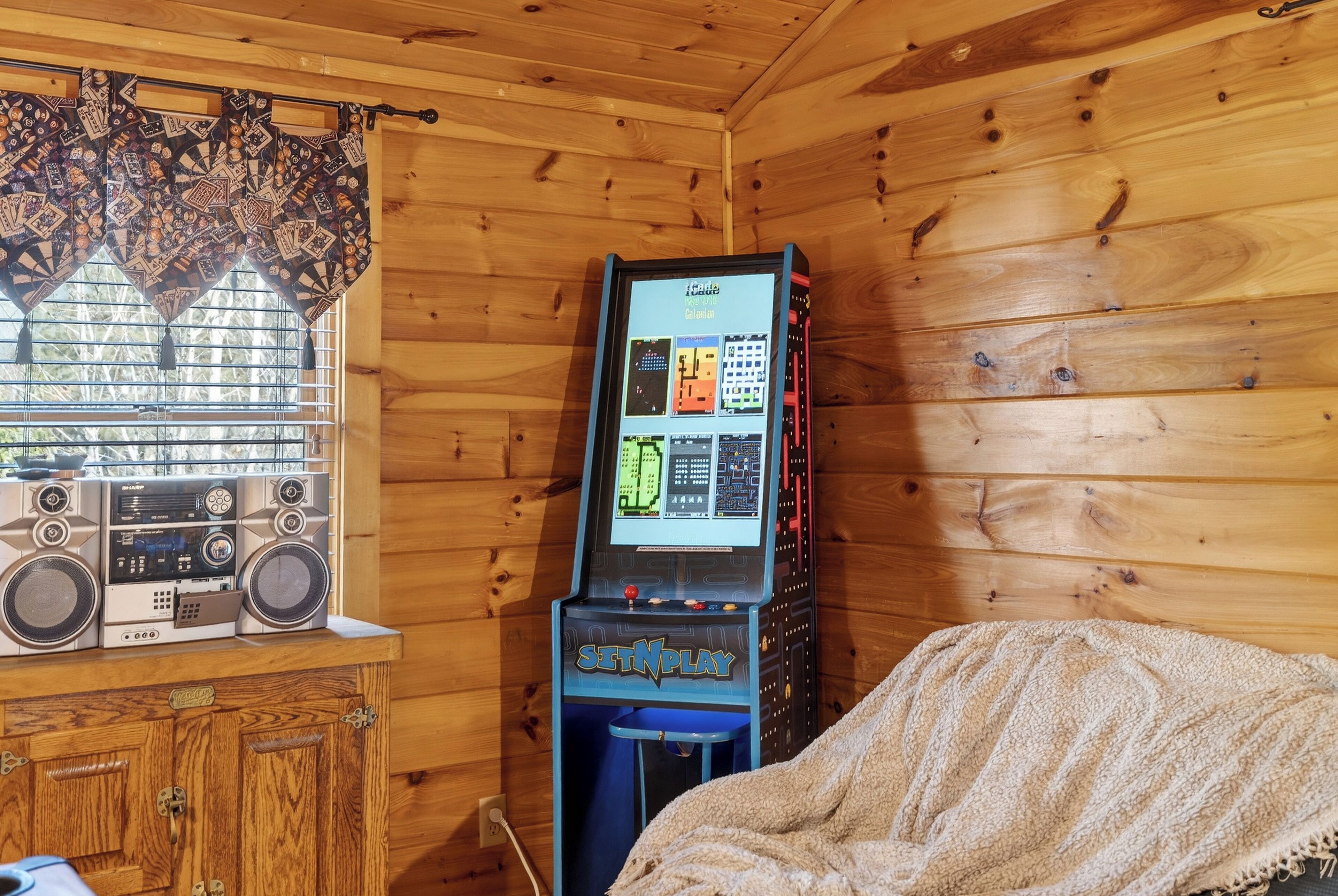 Een houten kamer met een vintage gokautomaat, een radio en een raam met patroon gordijnen.
