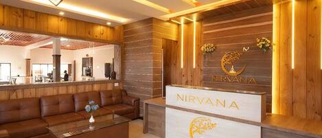 A reception area with a wooden reception desk, a brown leather sofa, and a coffee table.
