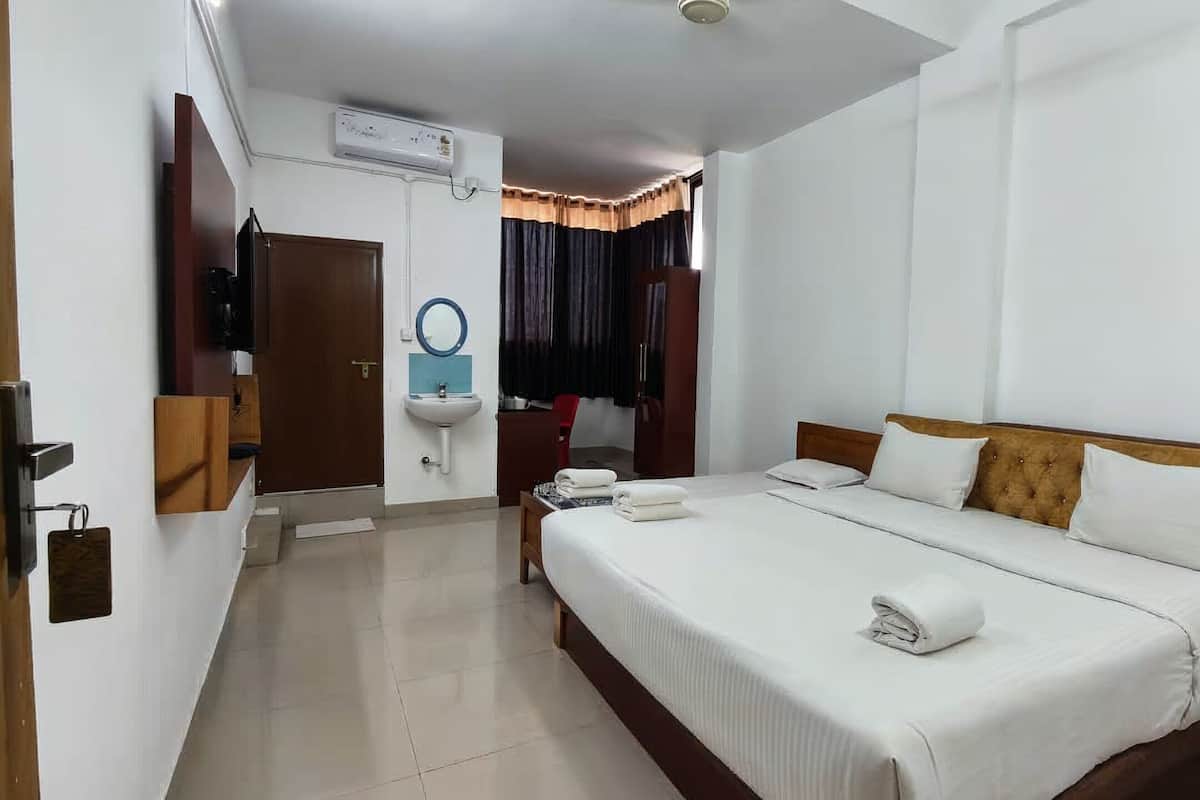 Een hotelkamer met een bed, nachtkastje, spiegel, wastafel en een airconditioning.