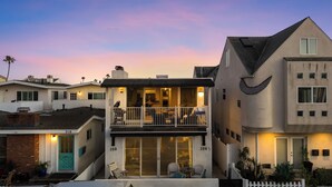 A two-story house with a balcony, a garage, and a driveway. - Top-Floor West Newport Retreat | Balcony | Near Beach + Cafes | Seabright Sky (Newport Beach)