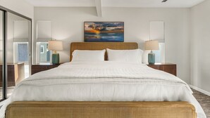 A hotel room with a large bed, two bedside tables with lamps, a ceiling fan, and a painting above the bed. - Top-Floor West Newport Retreat | Balcony | Near Beach + Cafes | Seabright Sky (Newport Beach)