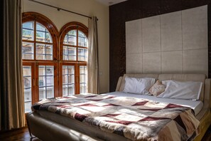 A bedroom with a large bed, a headboard, and a window with curtains. - White House By Kulut (Kullu)