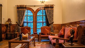 A room with a wooden sofa, a wooden table, and a window with curtains. - White House By Kulut (Kullu)