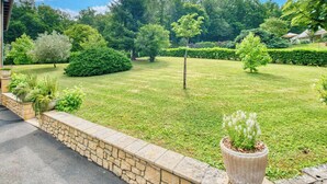 A well-maintained garden with a stone wall, various shrubs, and a large planter with white flowers. - Villa Forestière (Le Lardin-Saint-Lazare)