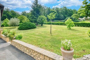 A well-maintained garden with a stone wall, various shrubs, and a large planter with white flowers. - Villa Forestière (Le Lardin-Saint-Lazare)
