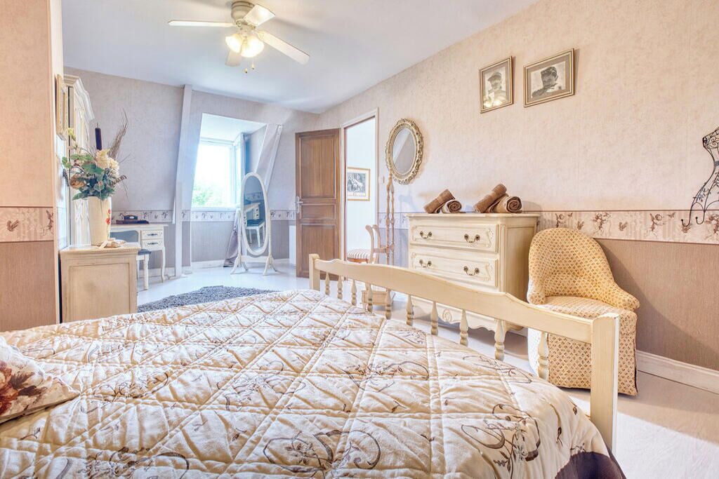 Une chambre à coucher avec un lit, une commode, une chaise et un miroir au mur.
