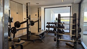 Ein modernes Fitnessstudio mit Krafttrainingsgeräten, Bänken und Kurzhanteln.