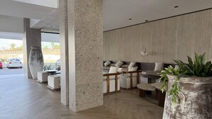 Eine moderne Lobby mit einer Sitzecke, großen Säulen aus Naturstein und Blick auf den Parkplatz.