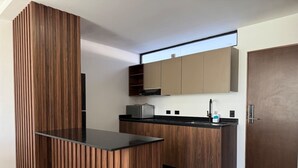Eine moderne Küche mit Holzausstattung, einer schwarzen Arbeitsplatte und einer eingebauten Mikrowelle.