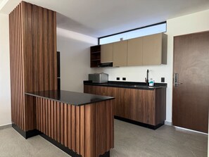 A modern kitchen with wooden cabinetry, a black countertop, and a built-in microwave. - In the Marina, With Pool and Nice Amenities (Mazatlán)