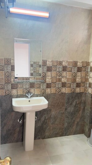 A bathroom with a pedestal sink, a mirror, and patterned tiles on the walls. - Mashobra Heights Hotel by Shalidrishya (Shimla)