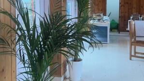 A wooden interior with a dining area, potted plants, and a view through the windows. - Mashobra Heights Hotel by Shalidrishya (Shimla)
