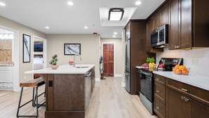 A modern kitchen with wooden cabinets, stainless steel appliances, and a central island. - Ski-In Ski-Out Home + Hot Tub + Resort Amenities + Alpine Views | Highline Lodge (Park City)