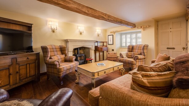 A cozy living room with plaid furniture, a fireplace, and a television. - Wisteria Cottage sleeping 8 (Helmsley)