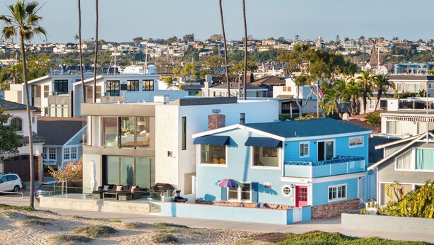 A modern coastal house with a blue exterior, large windows, and a visible garage.