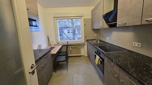 Een kleine keuken met een inbouwoven, een raam met uitzicht en een radiator.