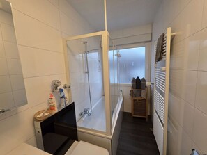 A narrow bathroom with a glass shower enclosure, a toilet, and a small sink. - Business apartment, 30+ nights – 80 m², 2 bedrooms (Leverkusen)