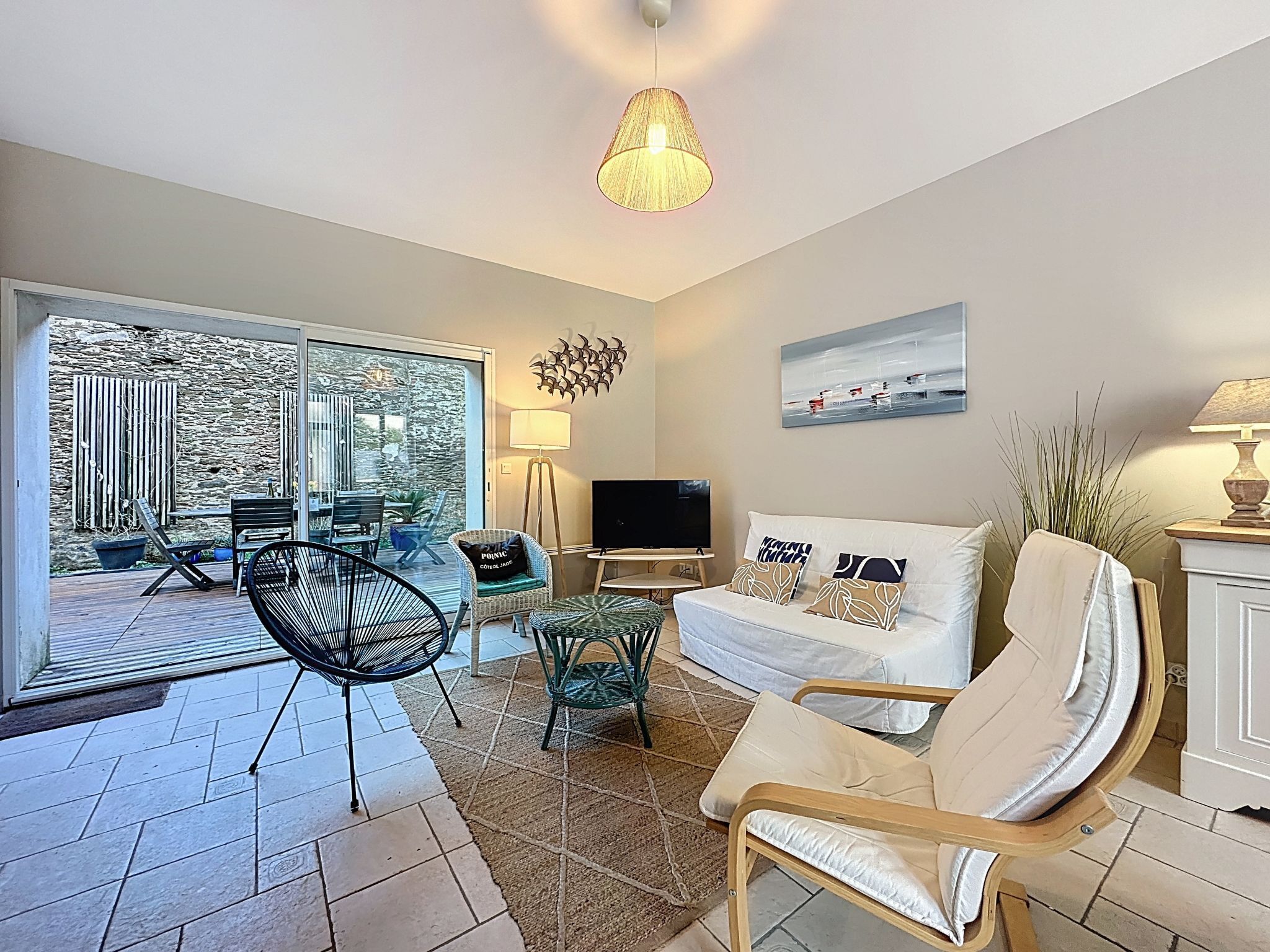 A modern living room with a sofa, chairs, a TV, and a dining area with a table and chairs.