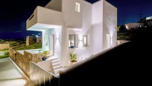 A modern white building with a staircase leading to a covered outdoor area, surrounded by greenery. - Eidolion Essence - Mykonos Villa with Private Pool (Mykonos)