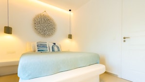 A bedroom with a bed, wall art, and two pendant lights. - Eidolion Essence - Mykonos Villa with Private Pool (Mykonos)