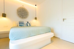 A bedroom with a bed, wall art, and two pendant lights. - Eidolion Essence - Mykonos Villa with Private Pool (Mykonos)