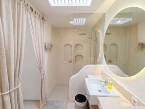 A modern bathroom with a skylight, a large mirror, a bathtub, and a sink. - Melvana Villa Uluwatu (Ungasan)