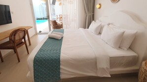 A hotel room with a bed, a desk, a chair, and a view of the beach. - Melvana Villa Uluwatu (Ungasan)