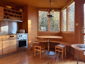 A wooden cabin interior with a kitchen, dining area, and large windows. - Large traditional chalet with all modern amenities, located 750 meters from the gondola (Ollon)