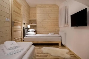 Ein kleiner, gemütlicher Raum mit einem Bett, einem Nachttisch, einer Lampe und einem an der Wand befestigten Fernseher.