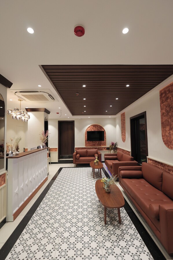 Um lobby moderno com balcão de recepção, sofás de couro, ladrilhos com padrão e teto com iluminação embutida.